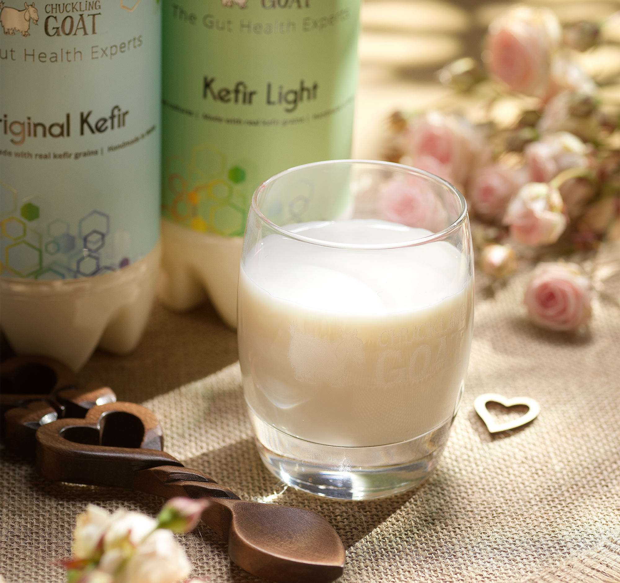 Glass of Chuckling Goat kefir in front of two bottles of Chuckling Goat Original and Light kefir