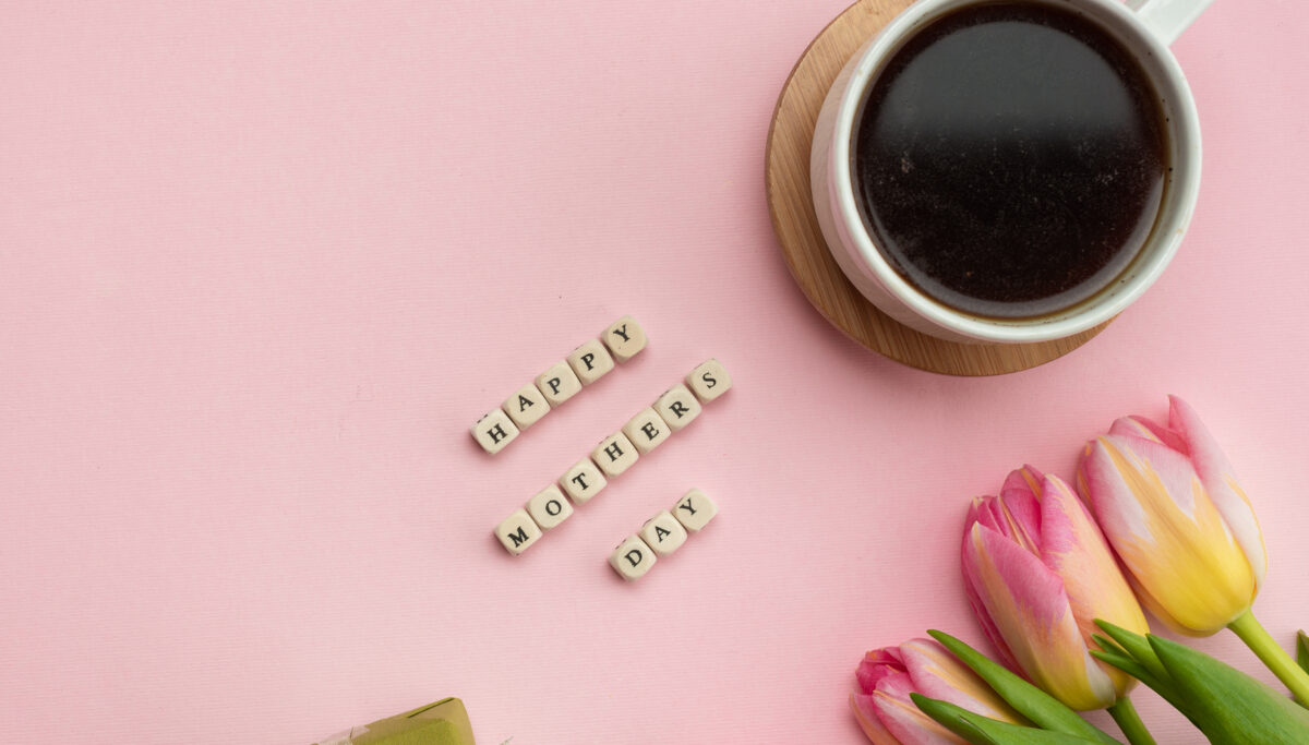 Mother's Day greeting message with tulips, gift and coffee on pink background. Background for International Mother Day.