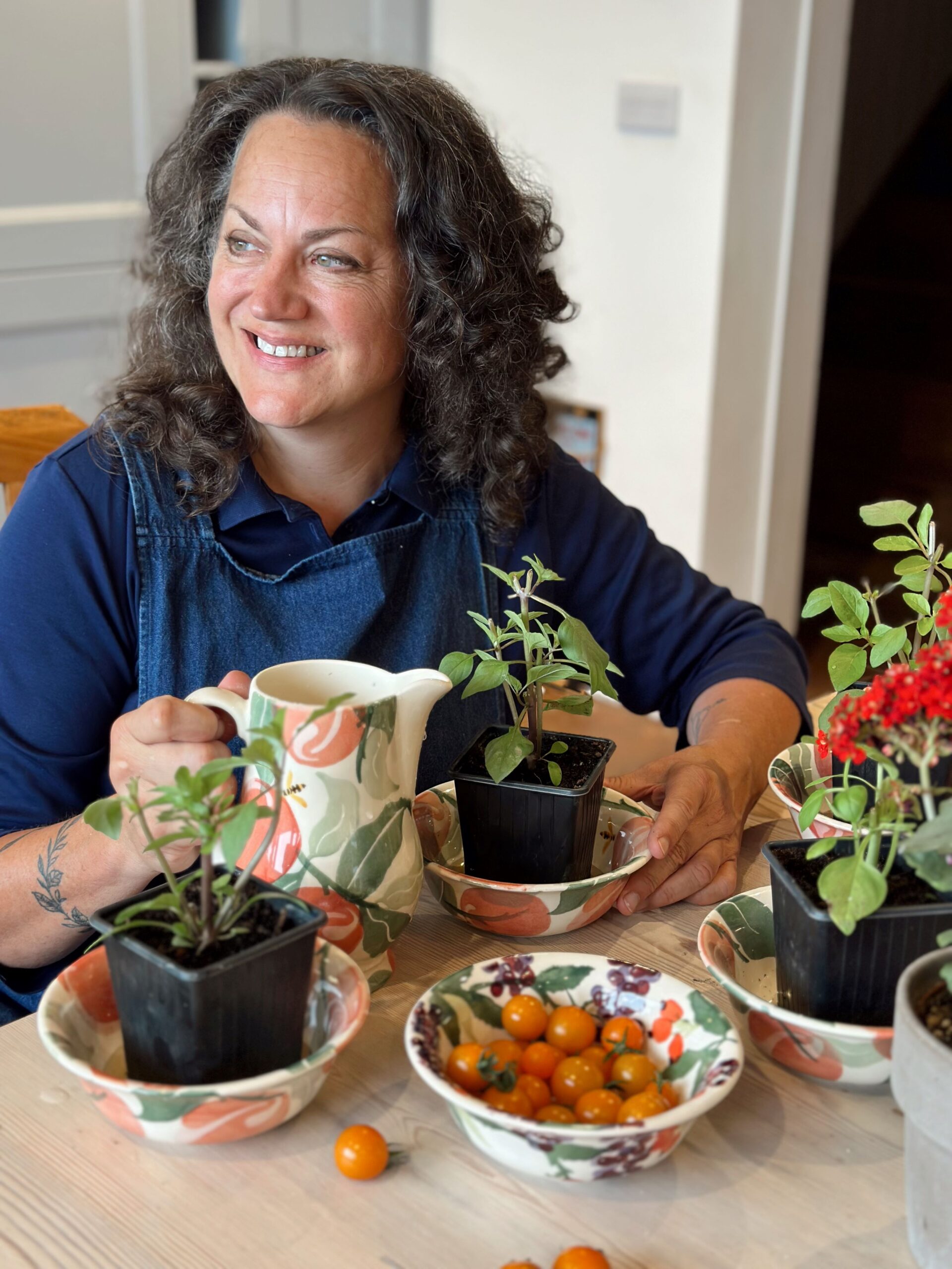 Image of Shann Jones, Chuckling Goat Director, smiling at table and watering plants.