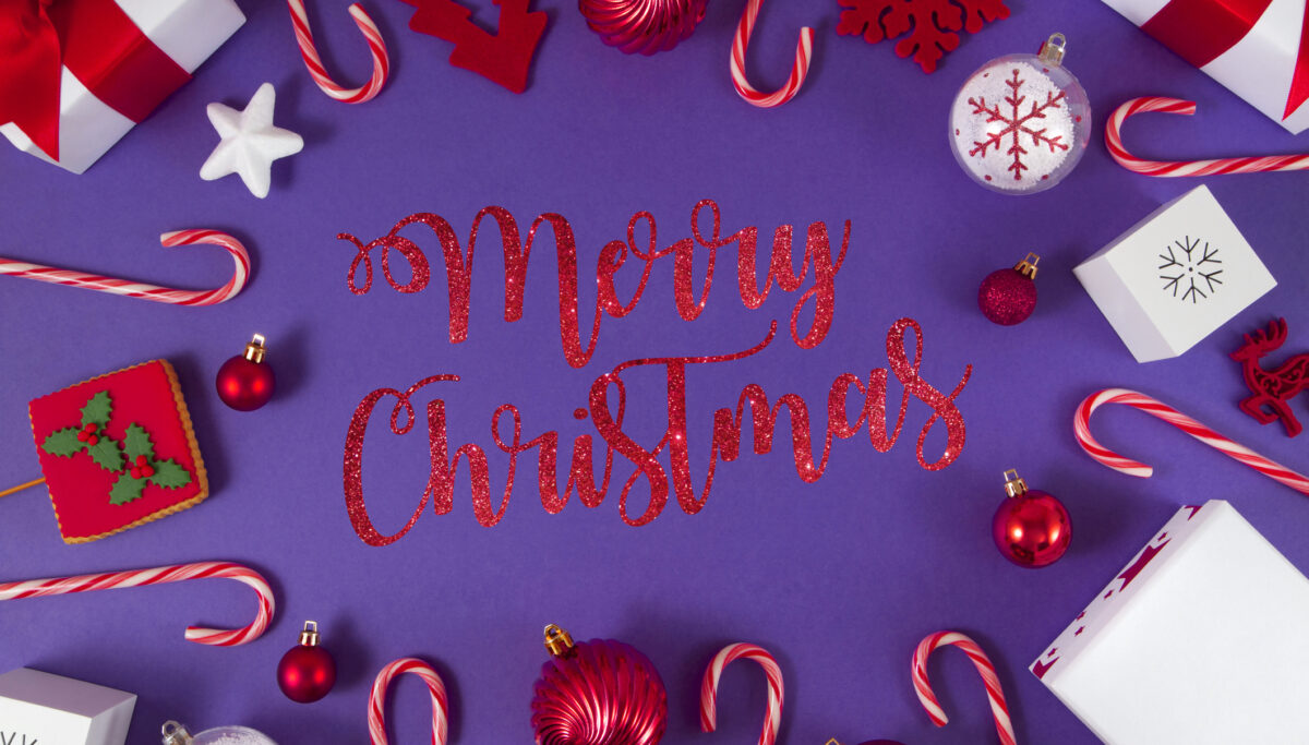 Christmas ornaments, gifts and candy canes on purple background. Says Merry Christmas.