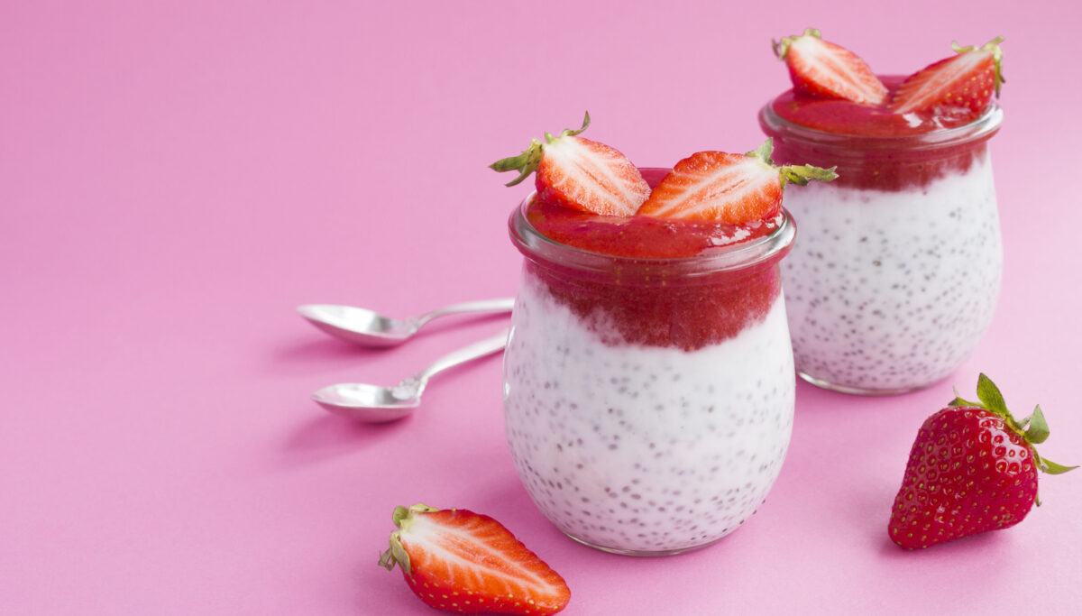 Pudding with chia and strawberry in the two glass jars on the pink background. Copy space. Closeup.