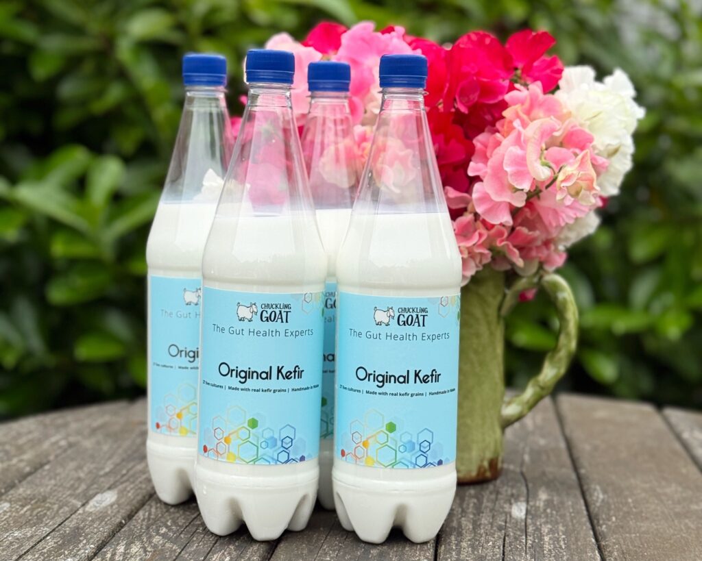 Image of Chuckling Goat Original Kefir bottles outside on table with flowers.