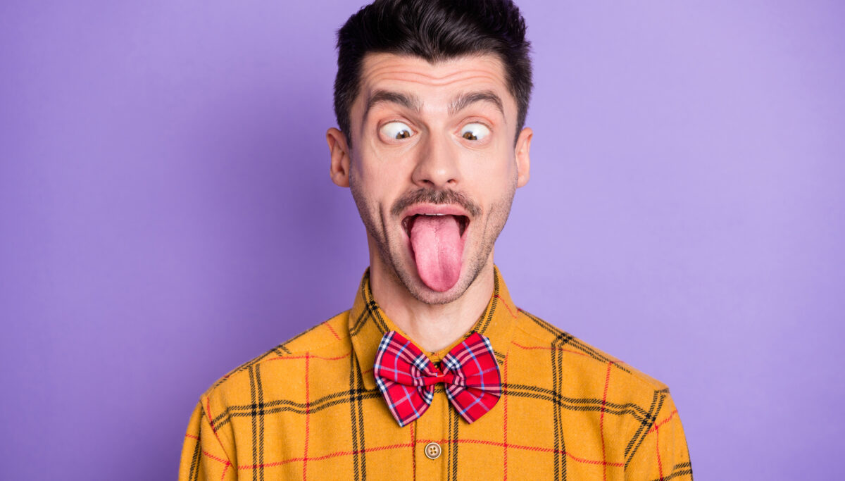 Photo of young brown hair man crazy carefree tongue-out fooling isolated over violet color background