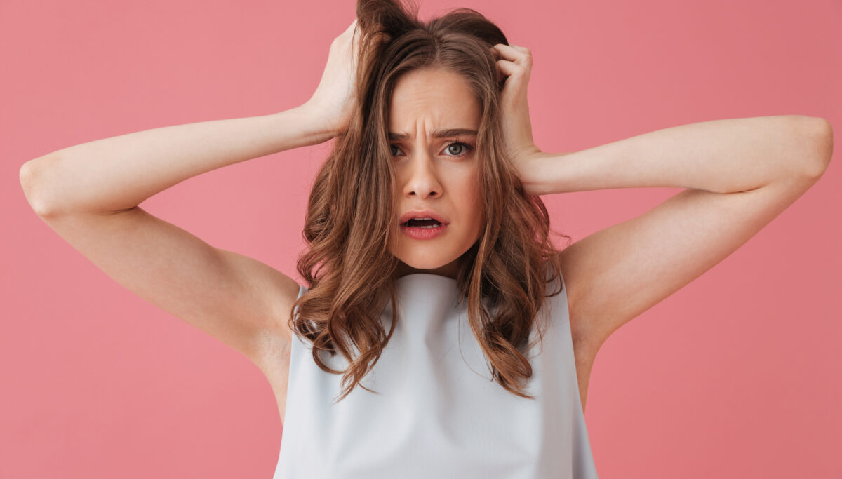 Image of shocked young woman standing isolated over pink background looking aside.