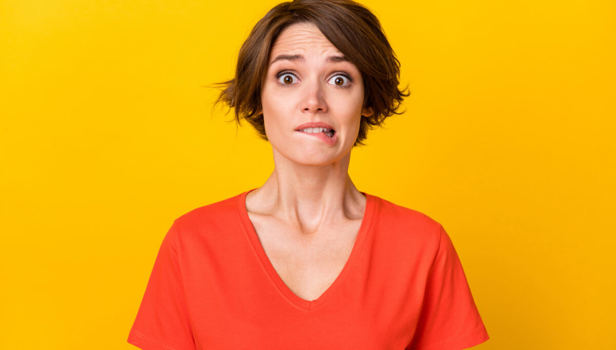 Photo of stressed woman looking unsure on a yellow background.