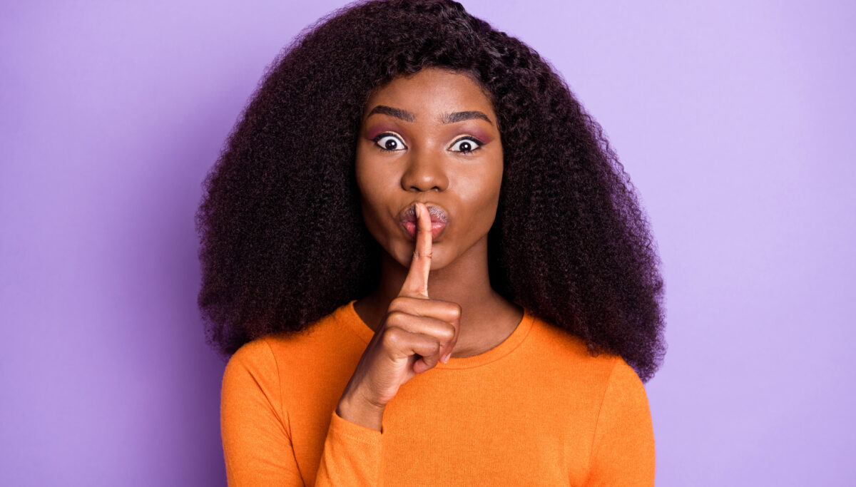 Photo of adorable cute young woman dressed orange ask not tell secrets finger lips isolated purple color background.