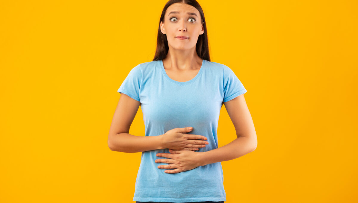 Surprised female model touching her stomach, feeling satiety after eating hearty meal, having good appetite