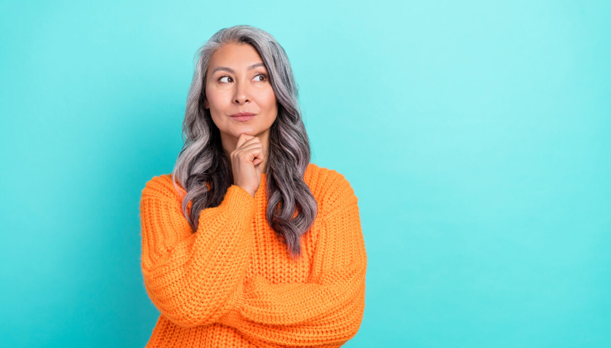 Thyroid health. Woman with hand on chin thinking, on a blue coloured background.