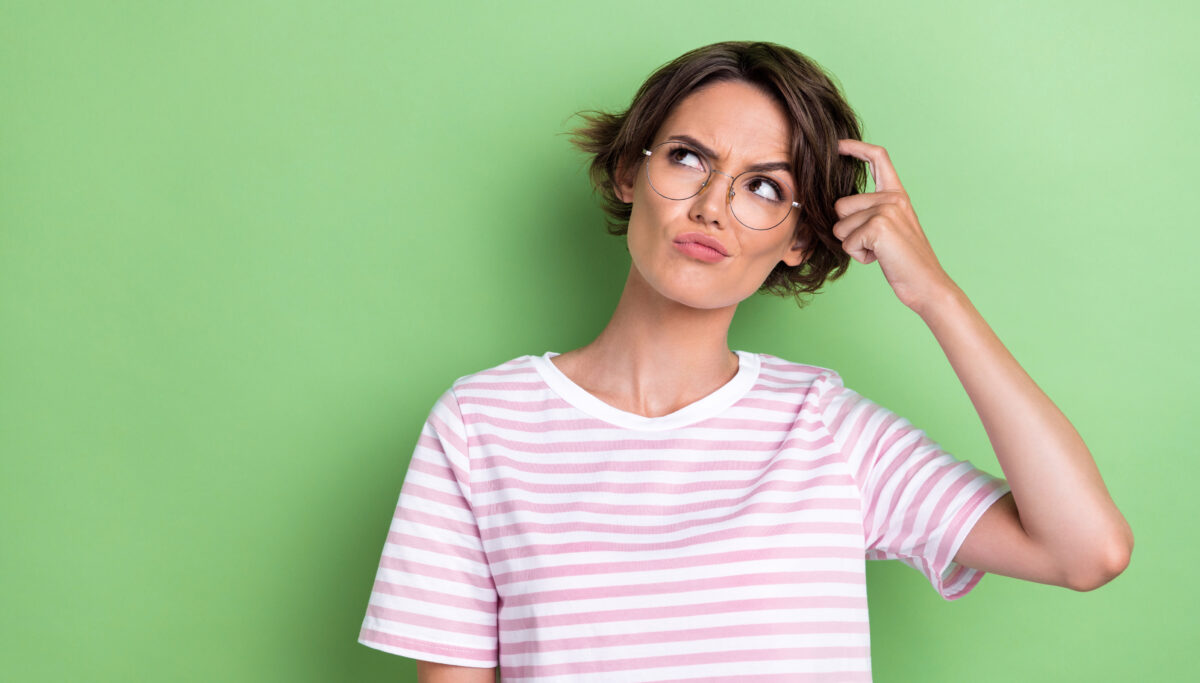 Photo of minded clever intelligent lady stylish outfit spectacles look empty space arm touch hairdo isolated on green color background.