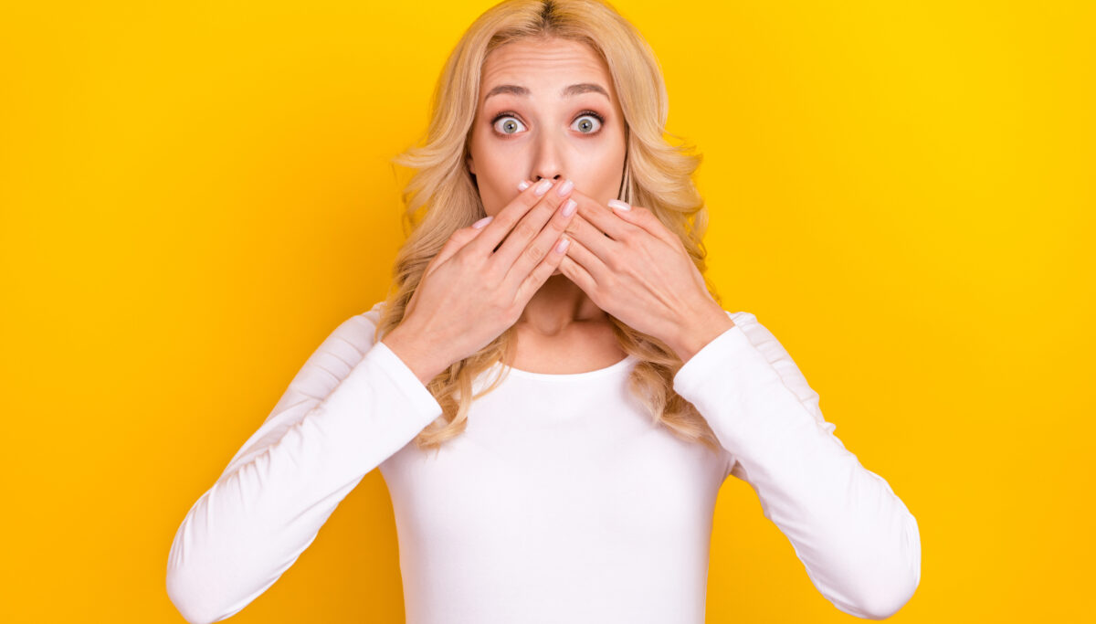 Photo of pretty lady dressed white shirt arms cover lips big eyes isolated yellow color background.