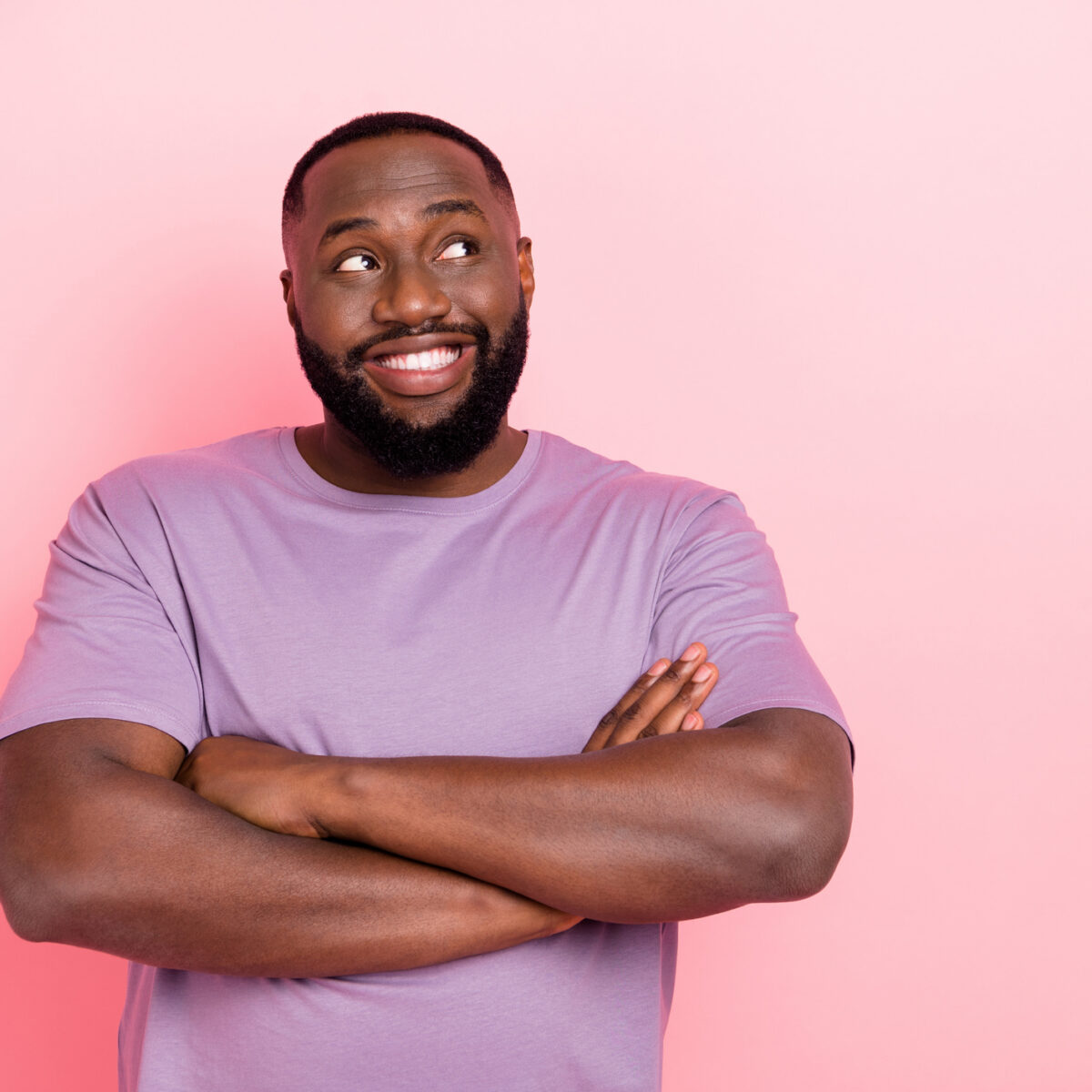 Photo of confident cheerful guy dressed violet t-shirt looking empty space arms folded isolated pink color background.