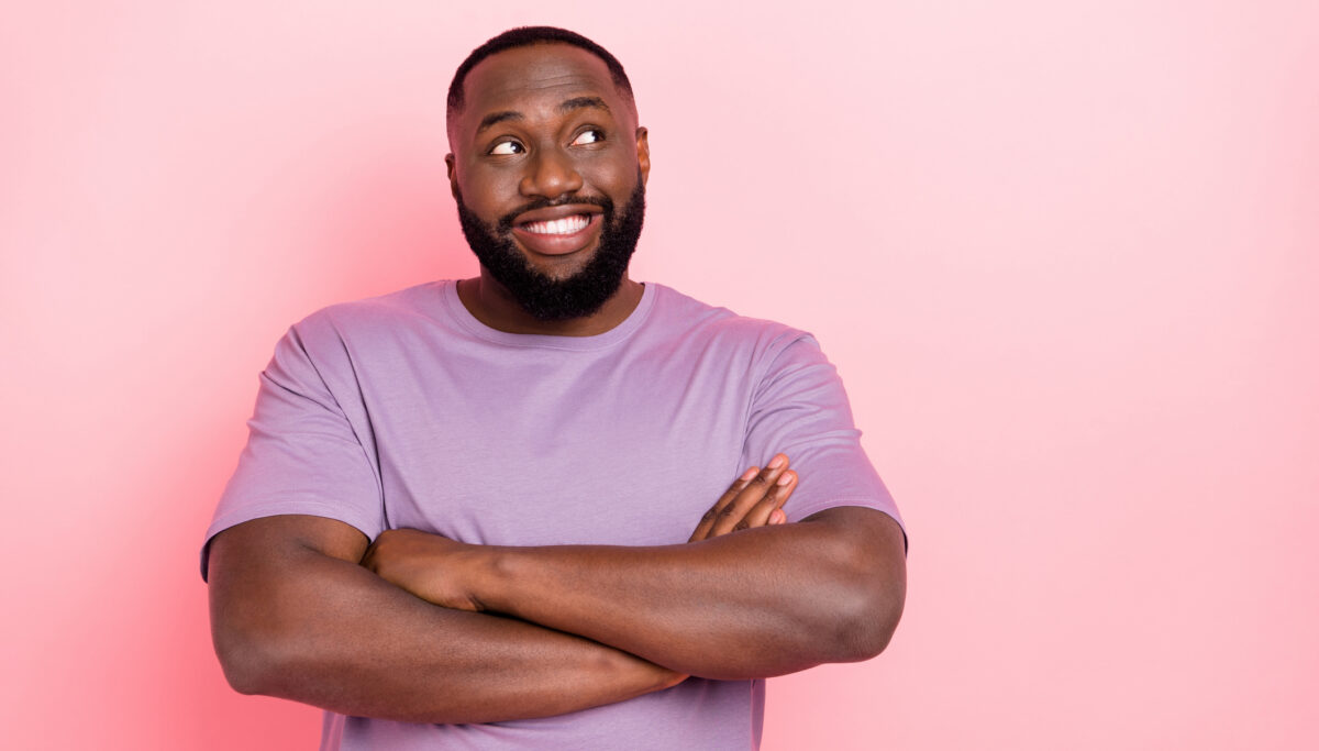 Photo of confident cheerful guy dressed violet t-shirt looking empty space arms folded isolated pink color background.