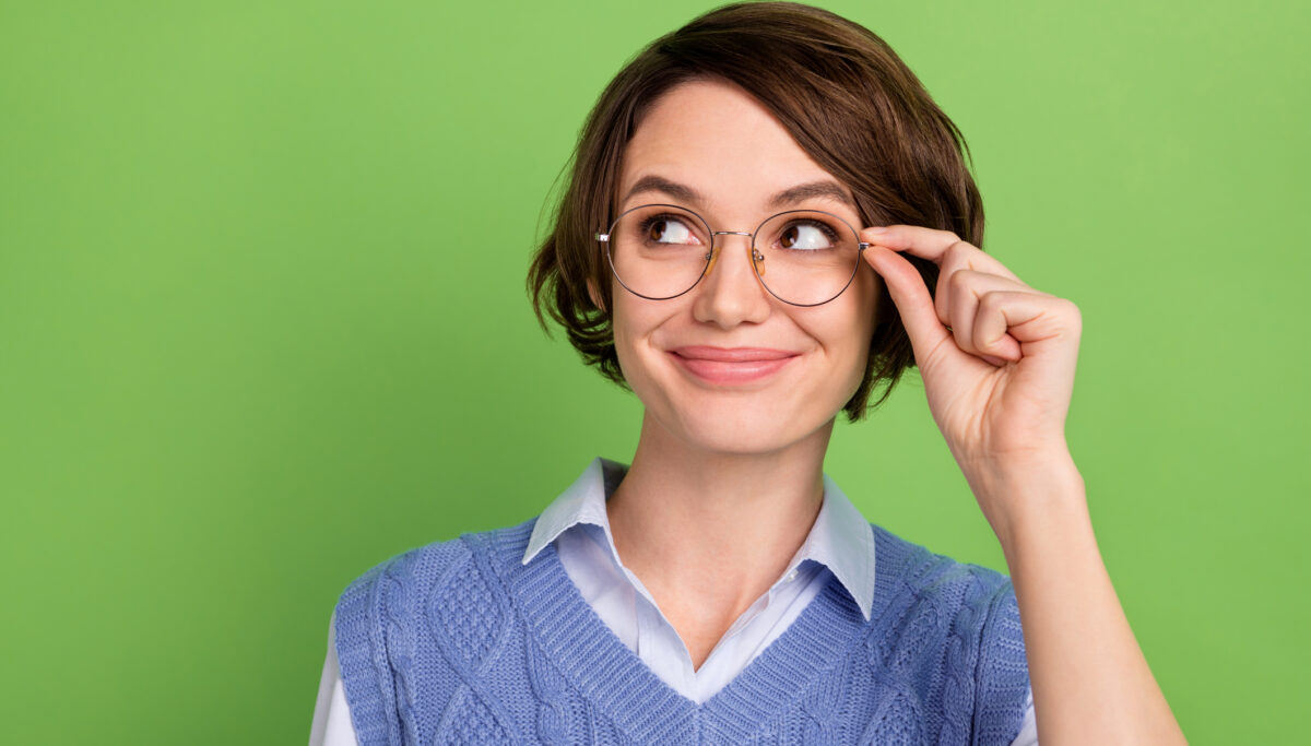 Photo portrait of clever woman in blue vest wearing glasses smiling looking copyspace isolated vibrant green color background