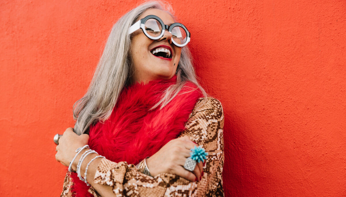 Cheerful senior woman laughing happily against a red wall