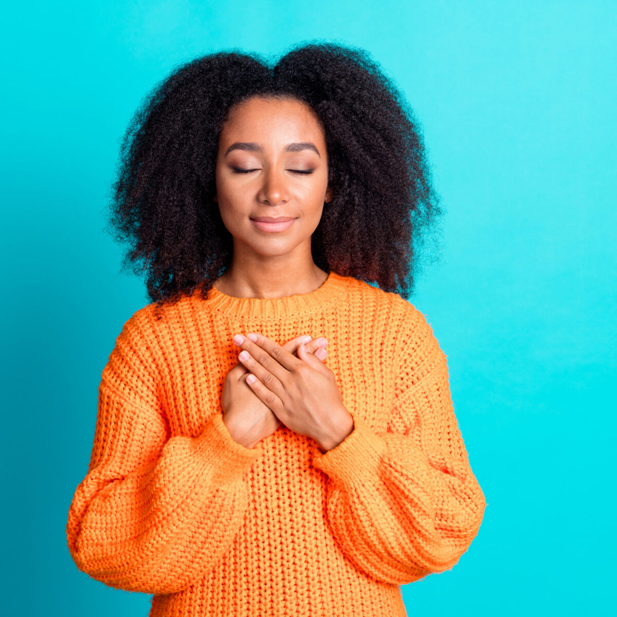 Photo of lovely young lady touch chest grateful closed eyes dressed stylish knitted orange garment isolated on aquamarine color background.