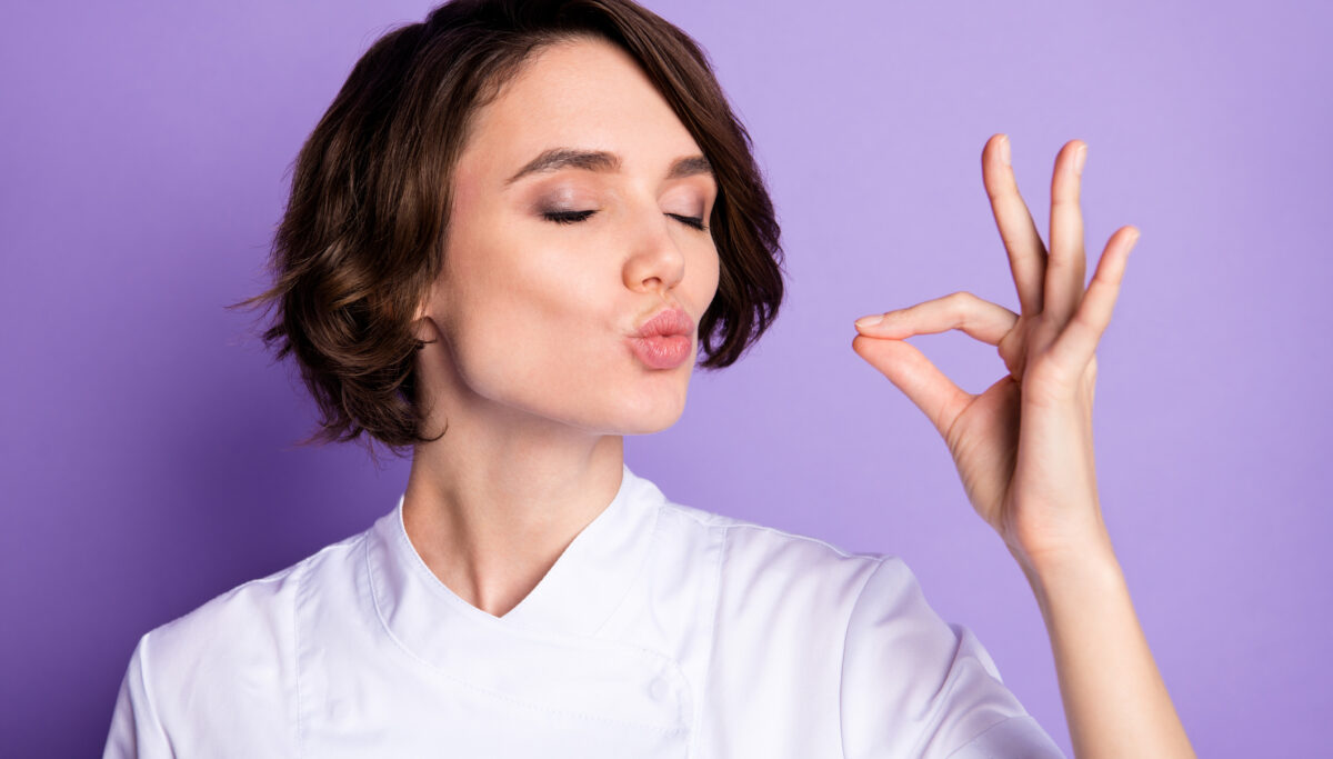Photo of charming happy young woman make gesture chef kiss tasty meal isolated on violet color background