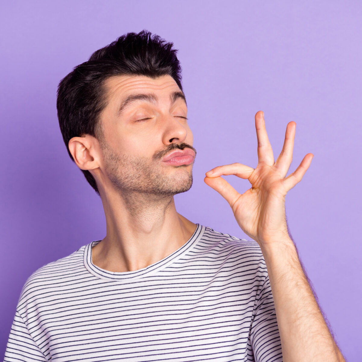 Young man, closed eyes trying delicious tasty food meal isolated on violet color background