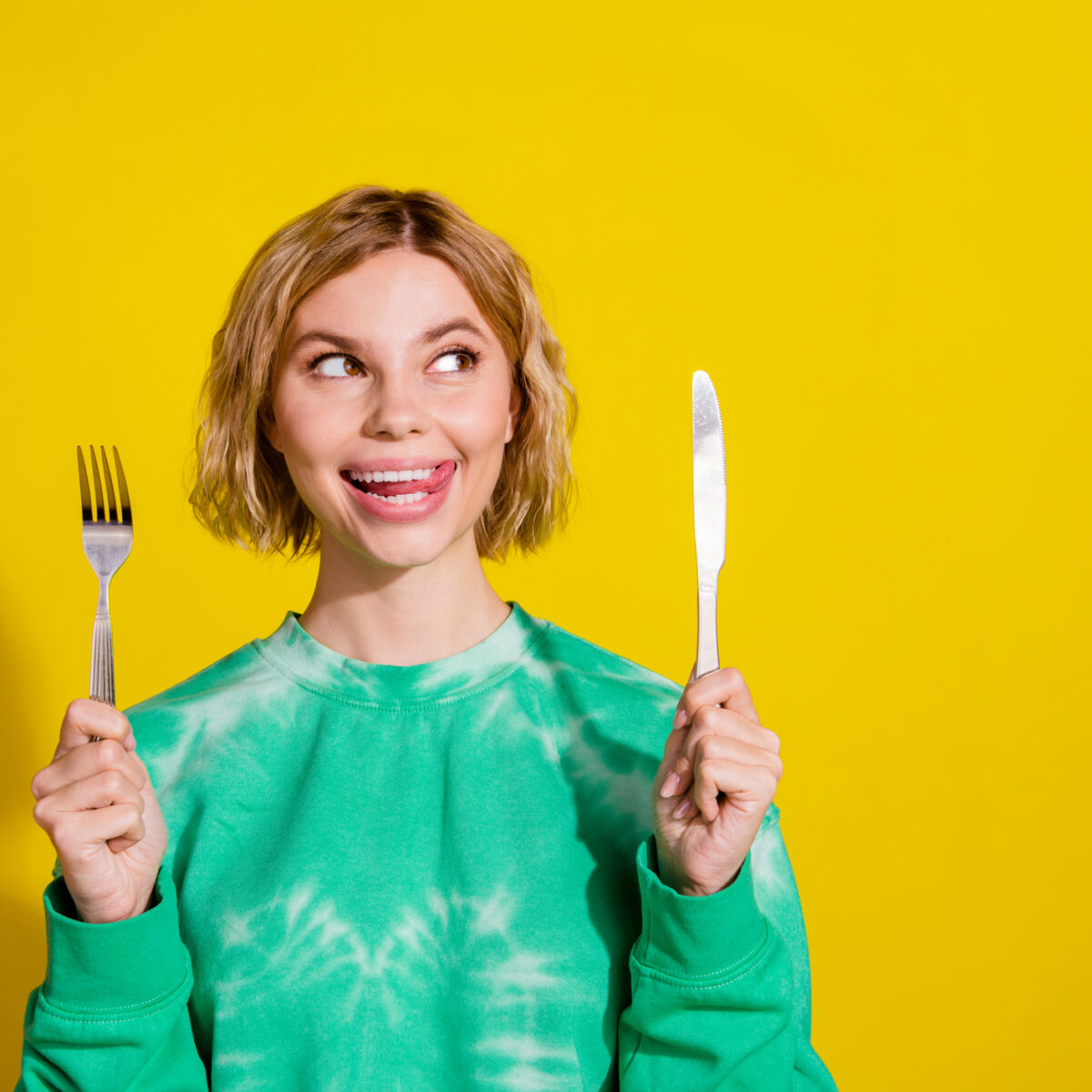 Photo of girl wear tie dye sweatshirt rising kitchen utencils looking empty space isolated yellow color background.