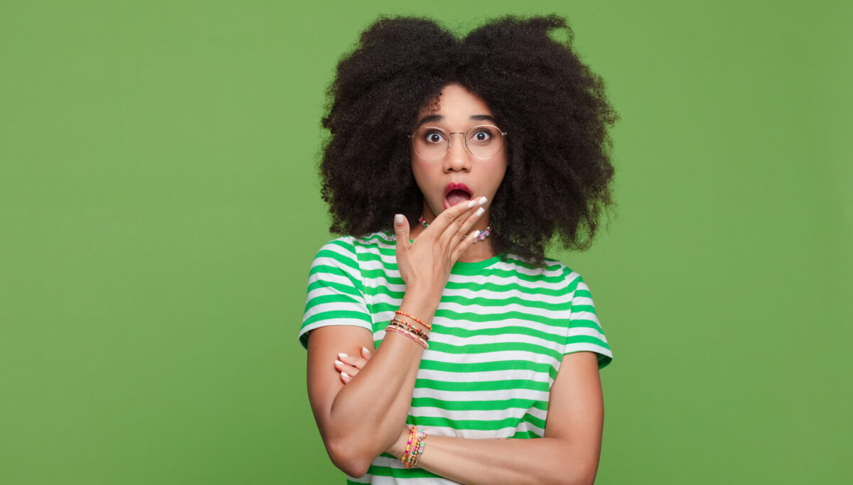 Leaking, urgency, rushing to toilet, Shocked afro-american woman, surprised, hand over mouth, on green isolated background