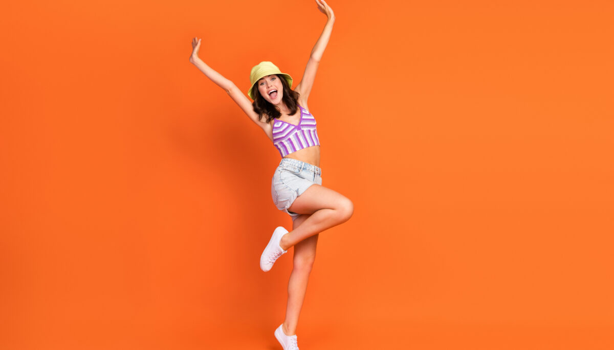 Summer fun, energy, photo of excited pretty lady purple swimwear having fun rising hands arms isolated orange color background.