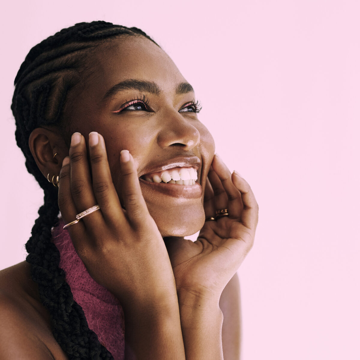 Collagen, summer skin, a close up shot of a beautiful young black woman smiling in front of a pink backdrop